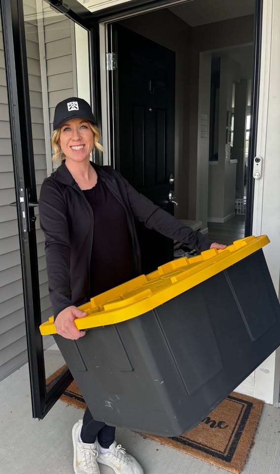 Kane County Tote Rental owner holding a black moving tote with a yellow lid at a front door